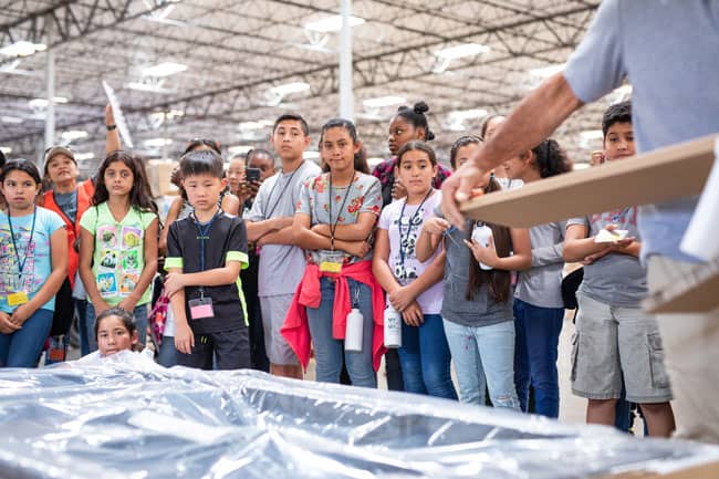 Students from Jiaxing City, China, and Norton Elementary School in San Bernardino, Calif., watch an adjustable bed base being assembled during a tour of Ergomotion&#39;s distribution center. The students took part in a two-week program focused on STEM learning.