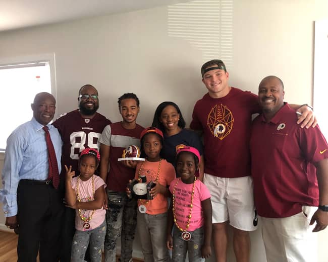 Washington Redskins linebacker Cole Holcomb (in Redskins T-shirt) and Bob’s Discount Furniture team members surprise Marvette James and her family with a Bob’s furniture delivery.
